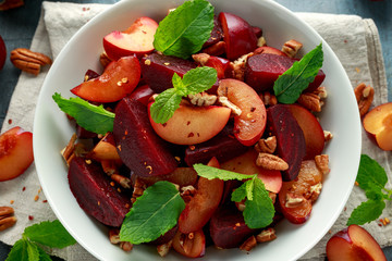 Vegan Plum, beet salad with pecan nuts, mint and herbs in white bowl. healthy summer food.