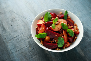 Vegan Plum, beet salad with pecan nuts, mint and herbs in white bowl. healthy summer food.