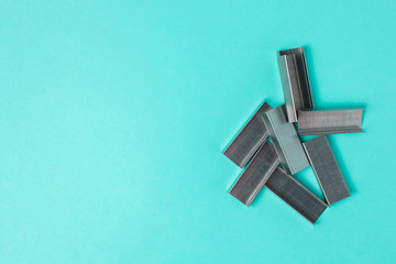 Scattered clamps for the stapler. office stationery accessories on a blue background with copyspace
