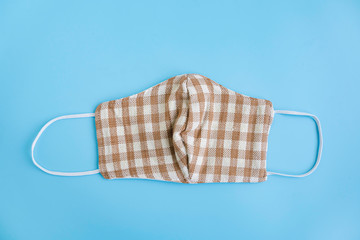 Handmade cotton face mask protective pollution, dust, or virus spread on color background. Coronavirus (COVID-19) preventive cotton mask, homemade face mask by fabric DIY concept. Top view, copy space