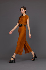 High fashion portrait of young elegant woman in brown overalls.