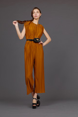 High fashion portrait of young elegant woman in brown overalls.