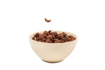 Chocolate corn flakes falling to the white bowl isolated on white. Motion.