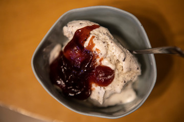 white vanilla ice cream with jam in a cup with a spoon
