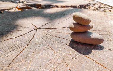 Yoga Zen stones balance on top of each other. Sea pebbles lies on a wooden saw lit by the sun. Copy space.