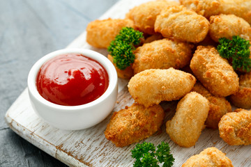 Crispy Battered scampi nuggets with ketchup on white wooden board