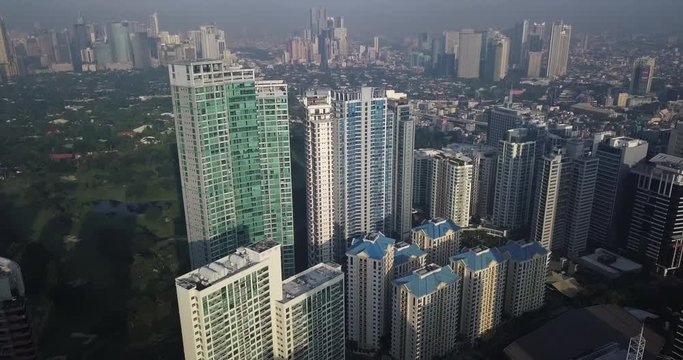 Forward aerial flight, tilt down, metropolitan view approaching high rise buildings. Drone, 4K.