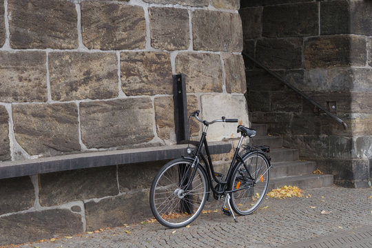 Altes klassisches Fahrrad abgestellt vor historischer Natursteinwand und Treppenaufgang
