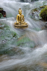 buddha sculpture is sitting in water cascade