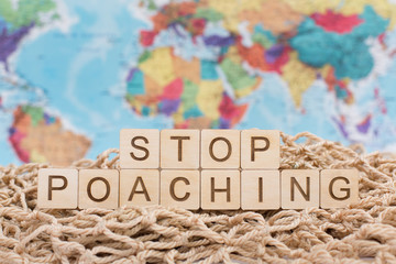 Wooden letters on world map background Stop Poaching sign, stop hunting concept