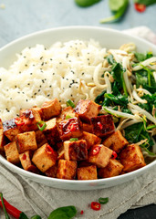 Fried tofu in sweet chilli glaze served with rice, steamed spinach and beansprouts in white bowl. Vegetable healthy food
