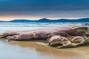 Stratocumulus Cloud Covered Sunrise Seascape and large rock on beach