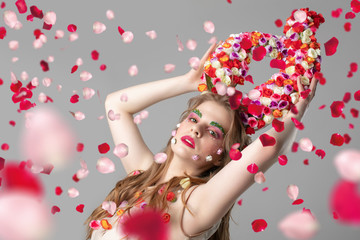Obraz na płótnie Canvas Portrait of a beautiful girl with flower horns in rose petals. Goddess Flora. Beautiful woman with fantastic makeup with flying flowers. Spring girl model.