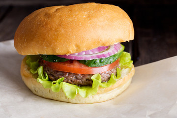 Close up tasty burger with beef, tomato, cucumber, onion and salad