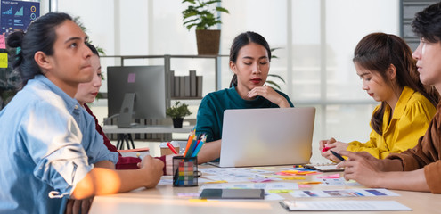 Serious meeting.asian female leader and ux developer and ui designer brainstorming about mobile app interface wireframe design on meeting table at modern office.Creative digital development agency