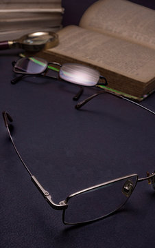Books with glasses on black table and wooden background. High resolution image depicting reading/bokks industry.