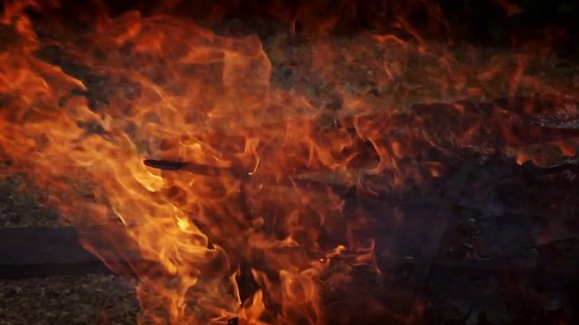 A wooden plank shaped like a sword burns on a bonfire