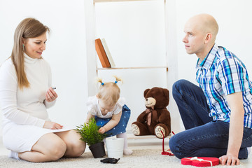 Happy family, mother, father and their baby together playing in living room at home. Children and toddler concept.