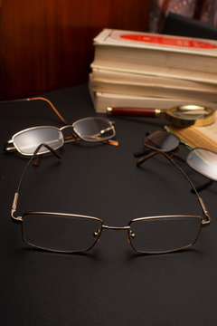 Books with glasses on black table and wooden background. High resolution image depicting reading/bokks industry.