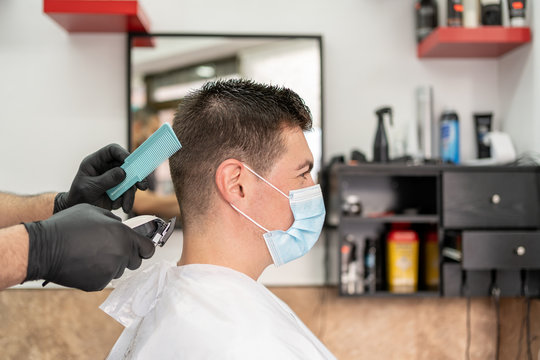 Man Getting Hair Cut At The Barbershop Wearing Mask. Covid-19 Concept.