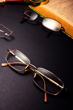 Books with glasses on black table and wooden background. High resolution image depicting reading/bokks industry.