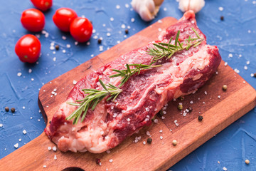 Fresh raw meat for steak on wooden cutting board.