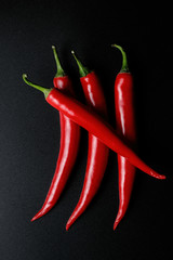 Fototapety  Cztery czerwone papryczki chili z czarnym tłem