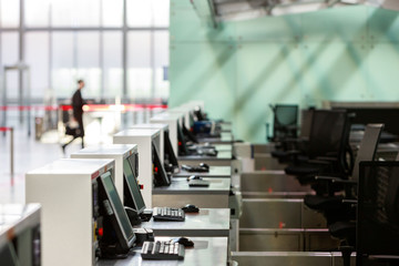 Fototapeta premium Row of check-in desks with computer monitors at empty airport terminal due to coronavirus pandemic/Covid-19 outbreak. Selective focus. Travel ban. 