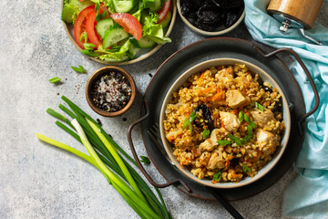 Bulgur pilaf. Healthy eating concept. Bulgur with chicken, vegetables and prunes on a gray stone or slate countertop. Top view flat lay background. Copy space.
