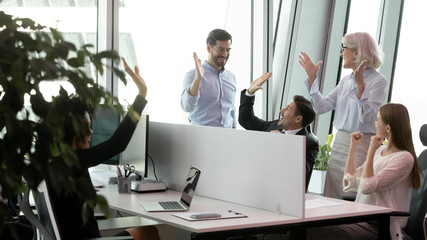 Group of joyful young and old businesspeople staff members gathered in co-working giving high five...