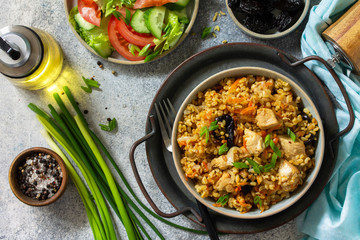 Bulgur pilaf. Healthy eating concept. Bulgur with chicken, vegetables and prunes on a gray stone or slate countertop. Top view flat lay background.