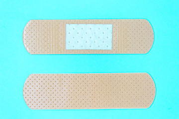 close-up of two skin color medicine adhesive healing bandage layout on blue background. wound healing patch concept