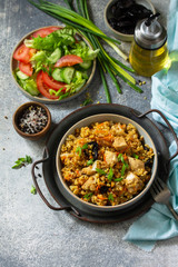 Bulgur pilaf. Healthy eating concept. Bulgur with chicken, vegetables and prunes on a gray stone or slate countertop. Copy space.