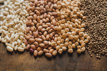 Mix of raw grains: lentils, chickpeas, brown and white beans  on the wooden table