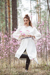 A girl dressed in Japanese style in a flowering forest among pink flowers