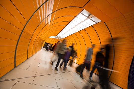 People rushing through a subway corridor (motion blur technique is used to convey movement)