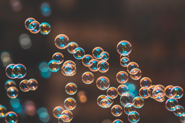Rainbow soap bubbles float on the air from the bubble blower. in teal blue color tone.