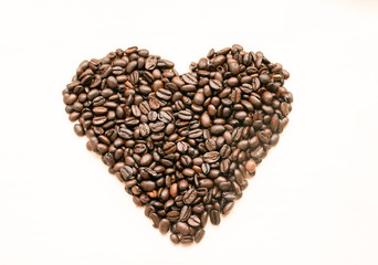 The shape of the heart is laid out on a light background of roasted coffee beans, there is room for text.