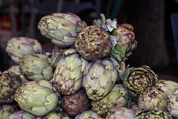 Obraz premium Fresh artichokes at farmers market. Local produce stack or pile for sale at the farmers market