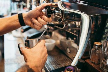 Close up shot of experienced barman or bartender hands making delicious and fresh espresso coffee drink on machine.