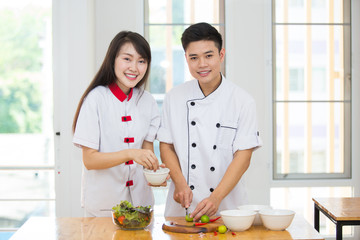 Two young Asian chefs helping each other Cook clean food with joy.