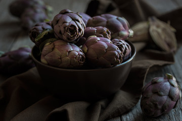 Fresh uncooked artichokes vegetables in a dark bowl, healthy food