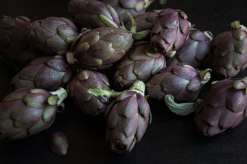 Obraz premium Fresh uncooked artichokes vegetables on dark background, healthy food