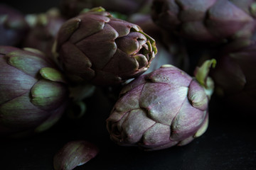 Obraz premium Fresh uncooked artichokes vegetables on dark background, healthy food