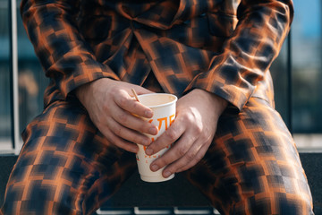 Men's hands hold a glass of coffee close-up on a sunny day