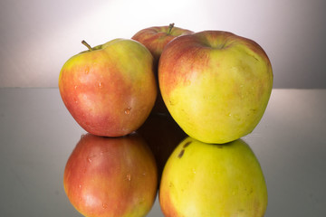 Three red apple on mirroring table. Gorizontal image with copy space.