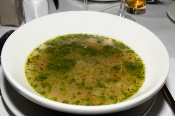 Classic Soup au pistou (pesto) in a white bowl being served in a restaurant. traditional authentic