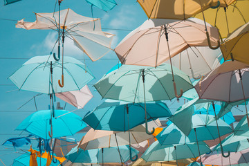 Colorful umbrella hang as ceiling with blue sky. in teal blue or pastel color tone.