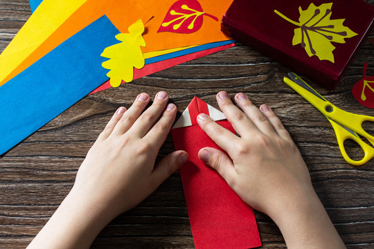Origami instruction step 5. Multicolored bookmarks origami paper pencil new school year on a wooden table. Welcome to school. Children's art project, needlework, crafts for children.