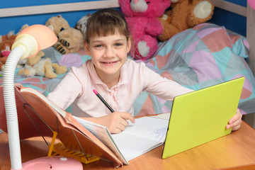 Cheerful girl doing homework using tablet computer